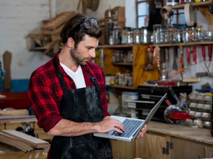Création site internet artisan : menuisier consultant son site sur un ordinateur portable dans son atelier