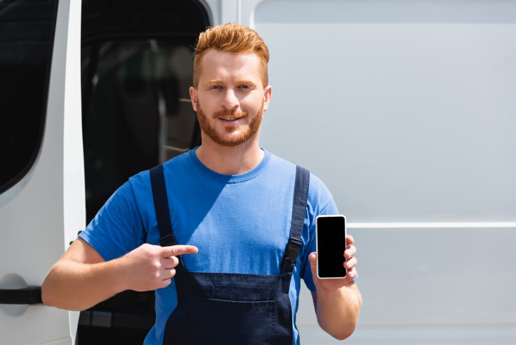Référencement naturel artisan : artisan présentant son smartphone devant son utilitaire